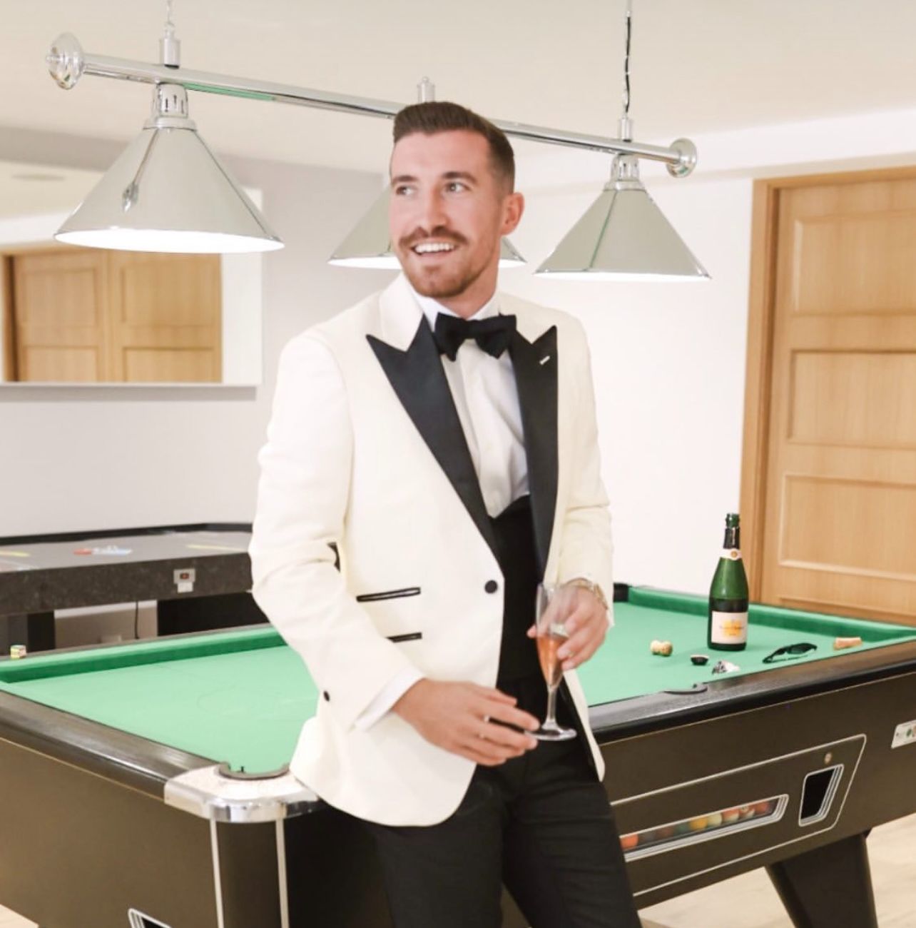 A man in a tuxedo is standing next to a pool table