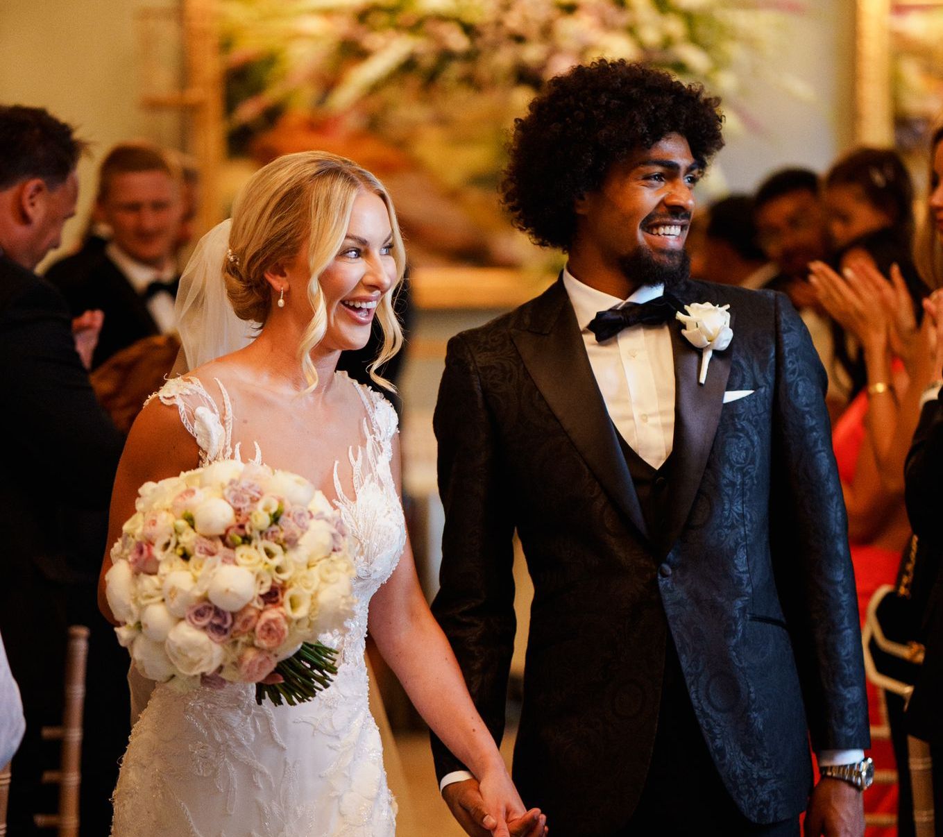 A bride and groom are walking down the aisle holding hands