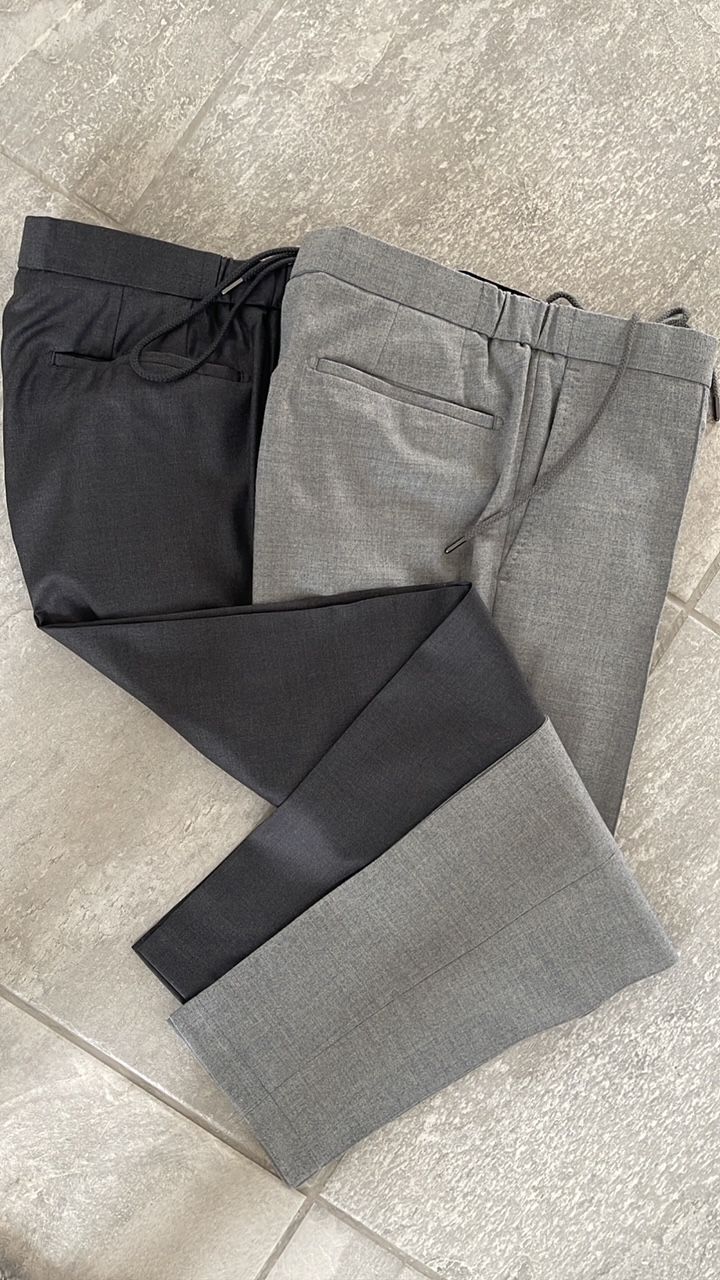 Two pairs of pants are sitting on top of each other on a tiled floor.