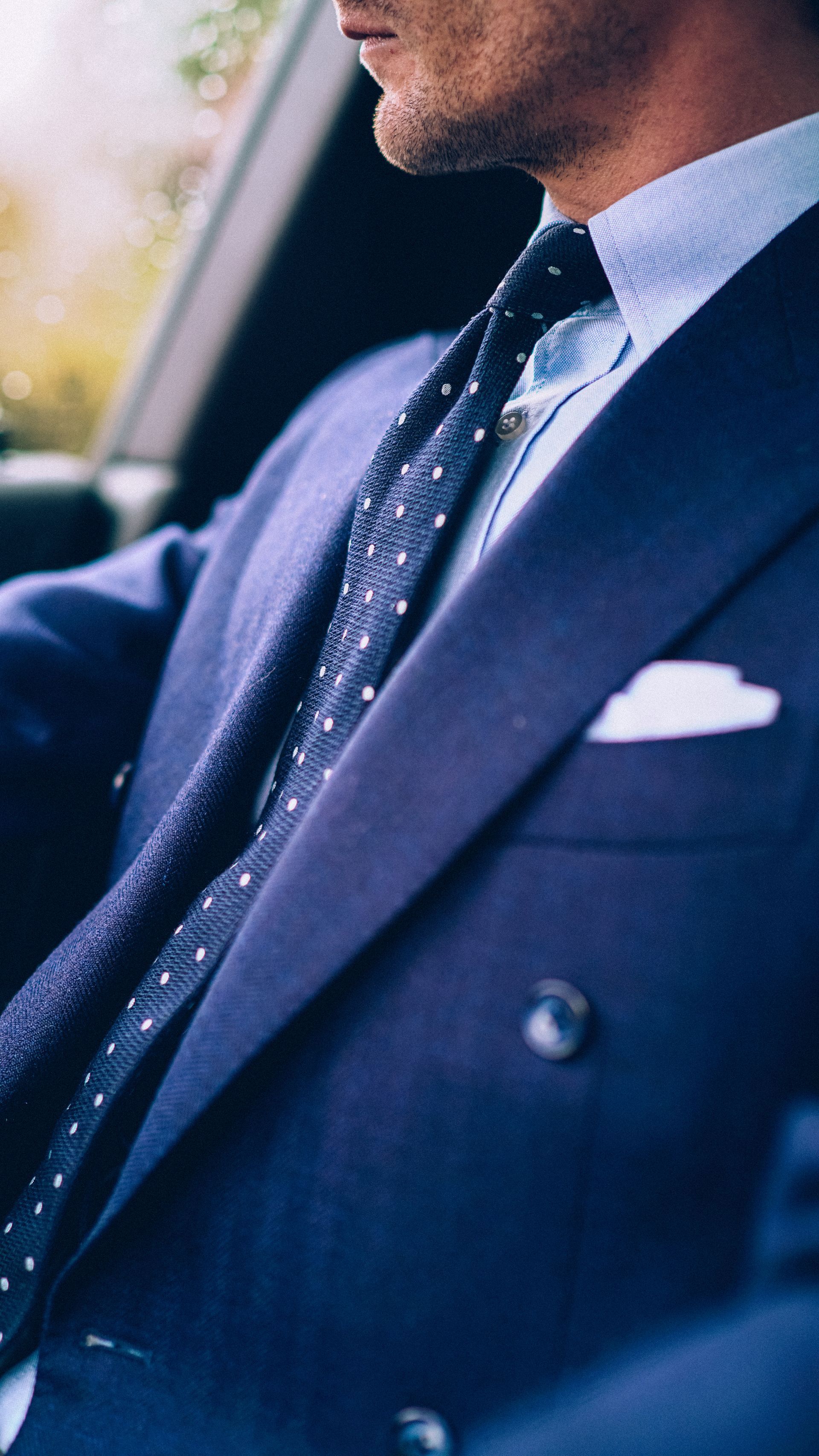 A man in a suit and tie is driving a car.
