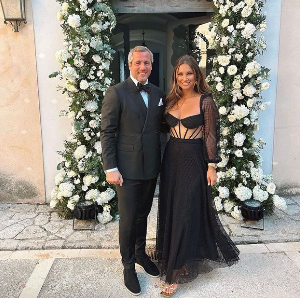 A man in a tuxedo and a woman in a black dress pose for a picture