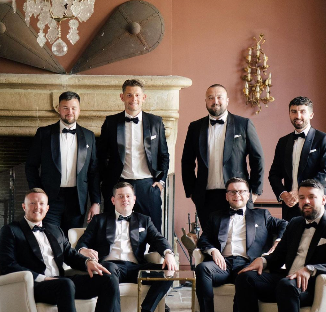 A group of men in tuxedos are posing for a picture