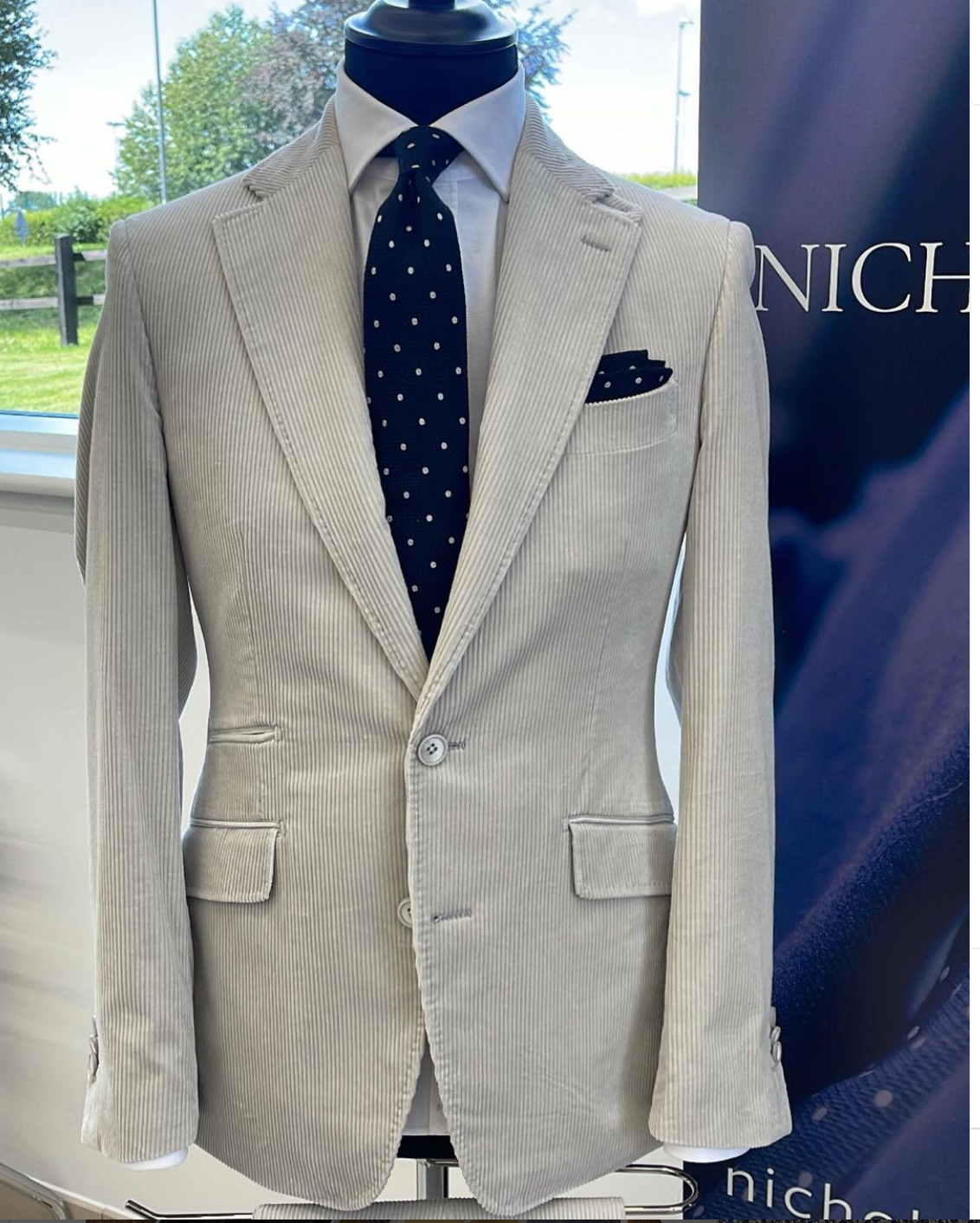 A white suit with a black tie is on a mannequin