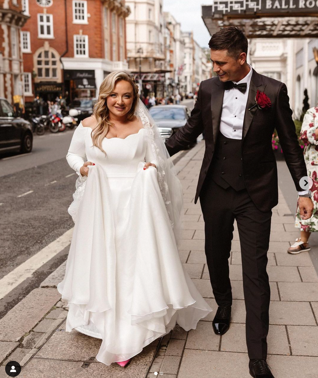 A bride and groom are walking down a sidewalk in front of a ball room