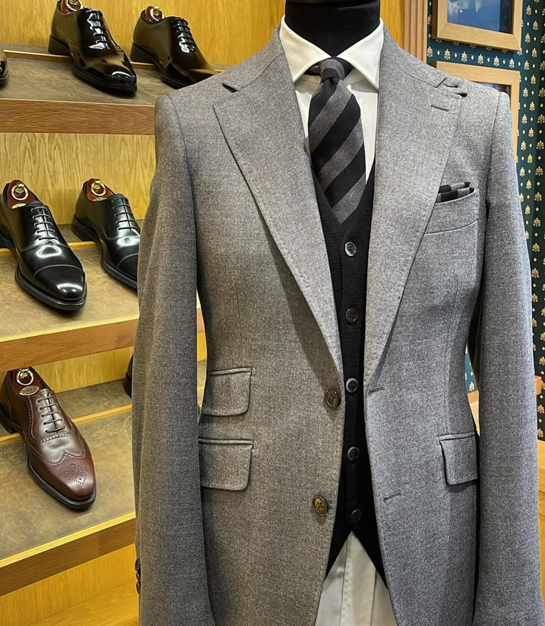 A man in a suit and tie is standing in front of a display of shoes