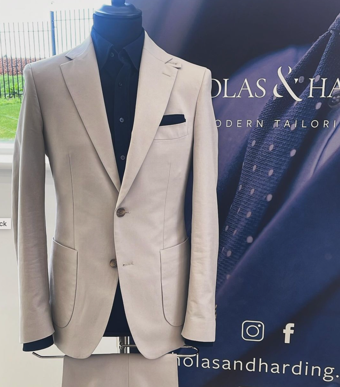A tan suit is on a mannequin in front of a sign that says olas & harding