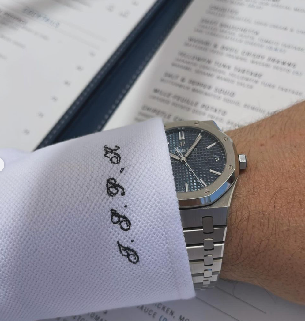 A man wearing a watch and a white shirt with the letters bb on it