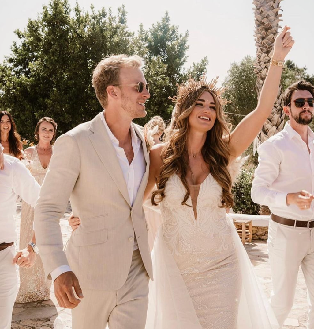 A bride and groom are walking with their wedding party