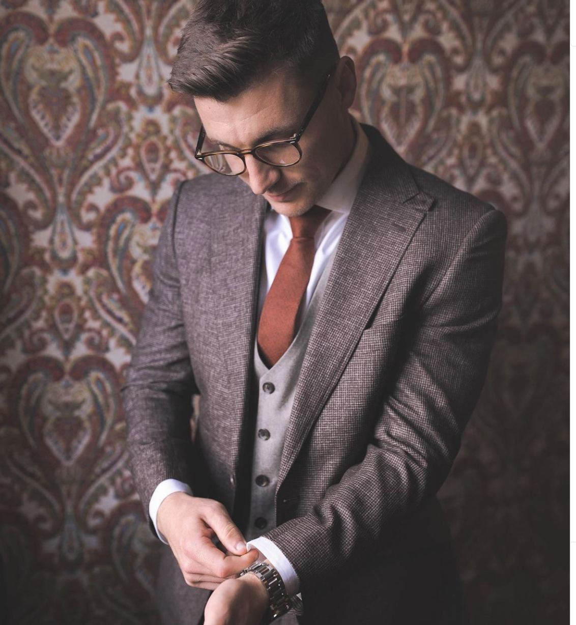 A man in a suit and tie is looking at his watch