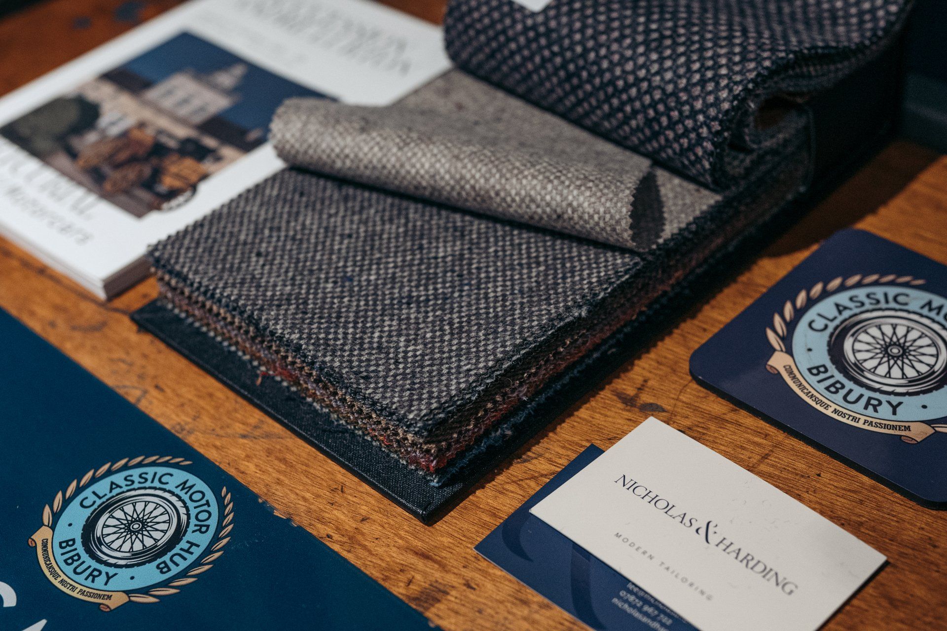 A stack of fabric samples and business cards on a wooden table.