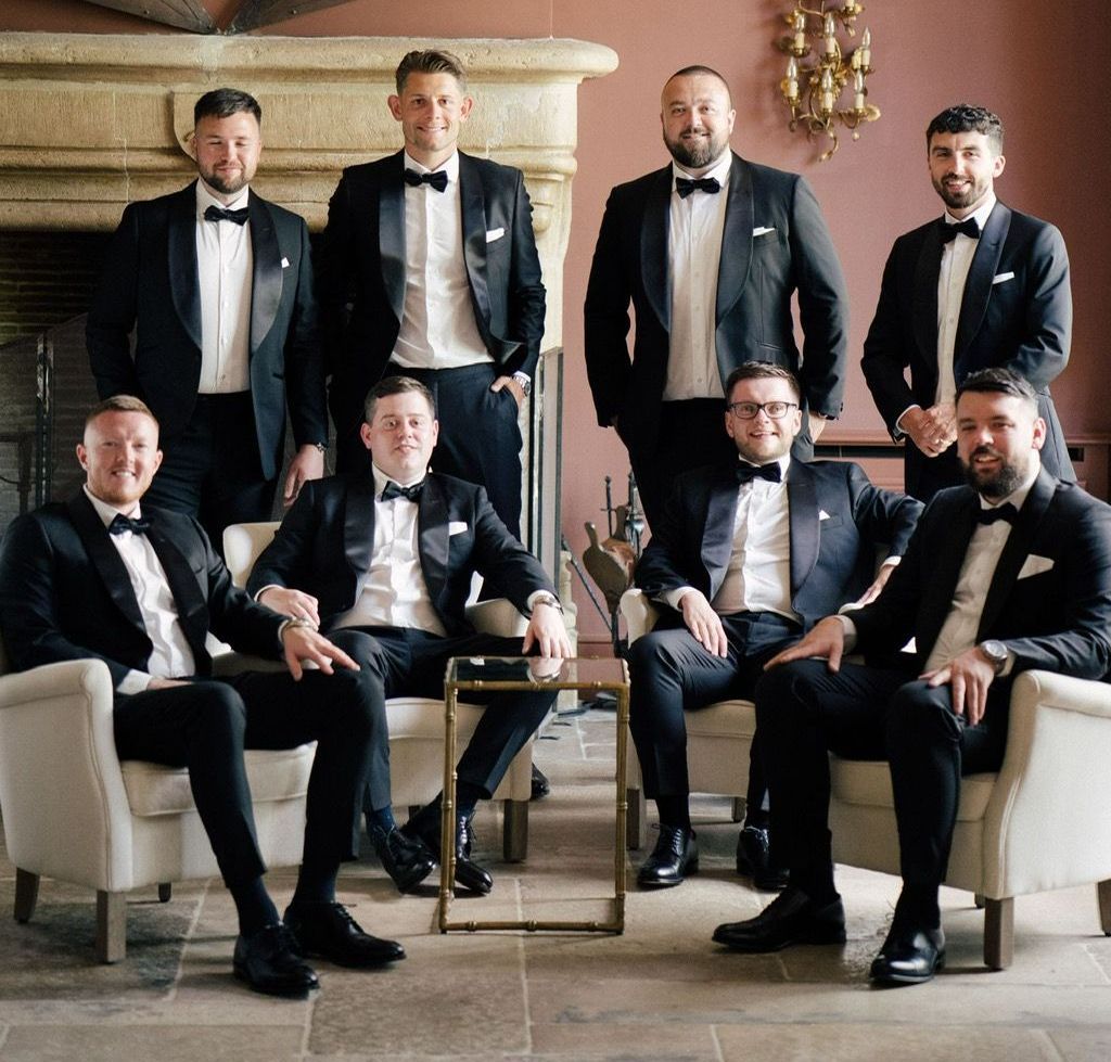 A group of men in tuxedos are posing for a picture