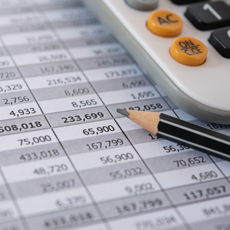 Calculator and pencil on top of a spreadsheet with numerical data.