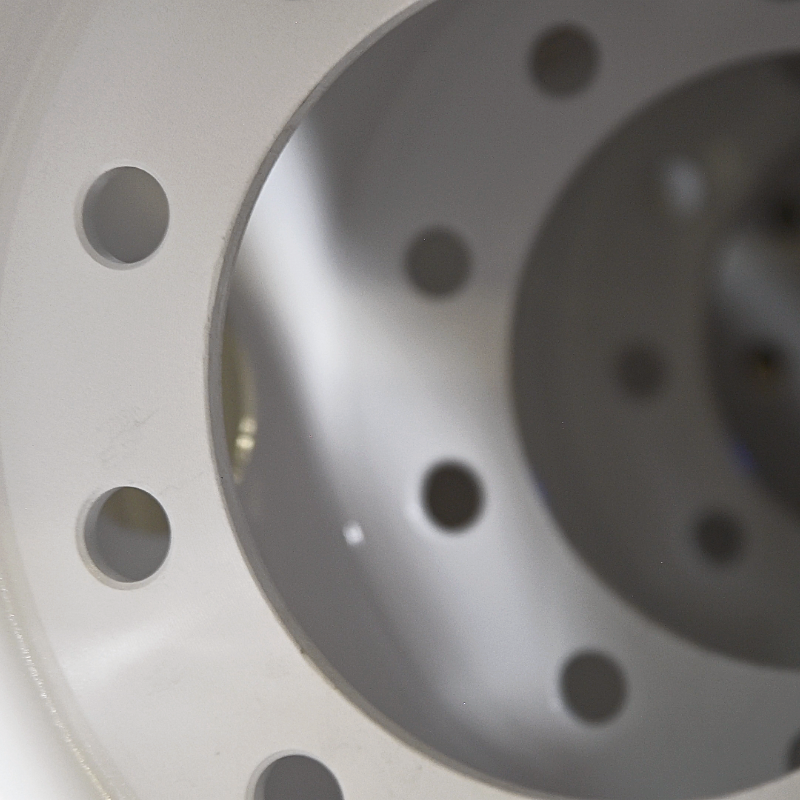 Close-up of a metal flange with circular bolt holes, reflecting light.