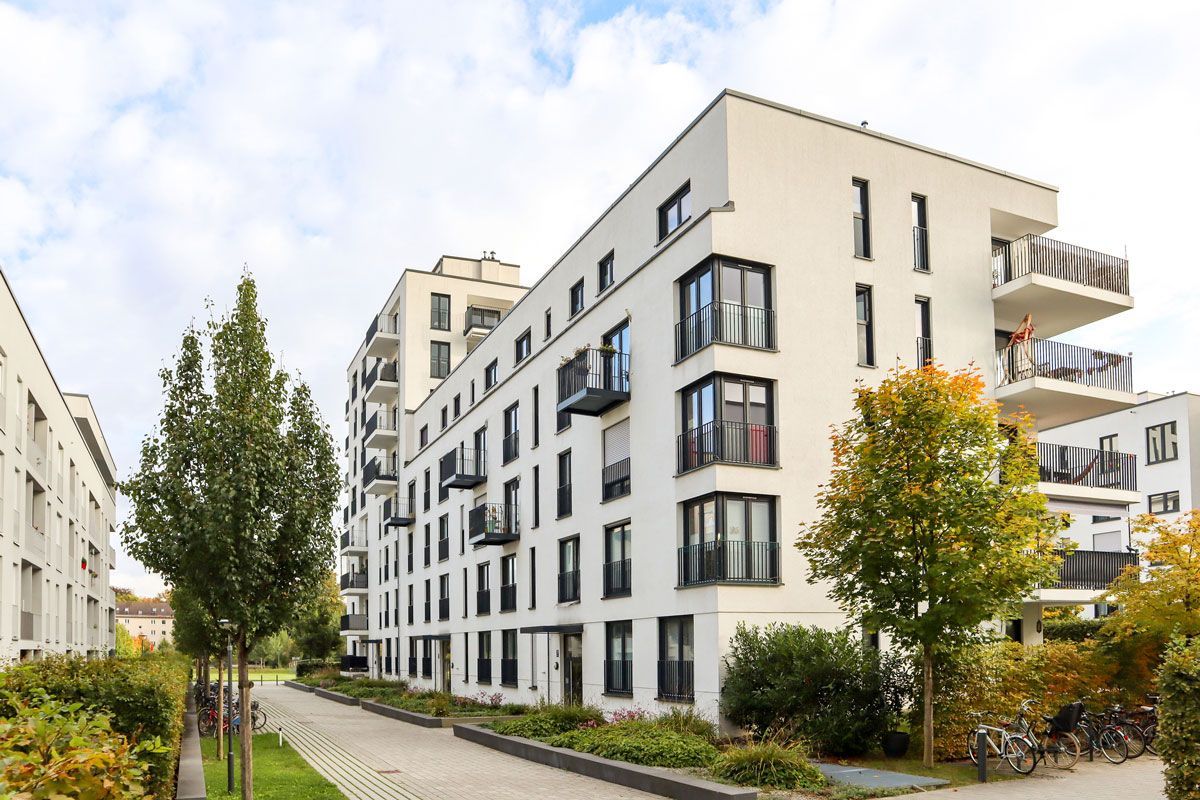 A large white apartment building with a lot of windows and balconies in a residential area.