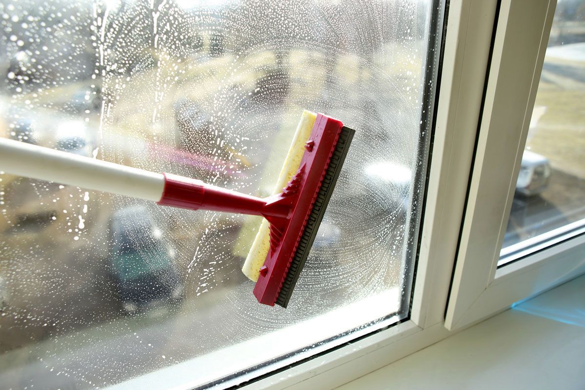 A person is cleaning a window with a squeegee.