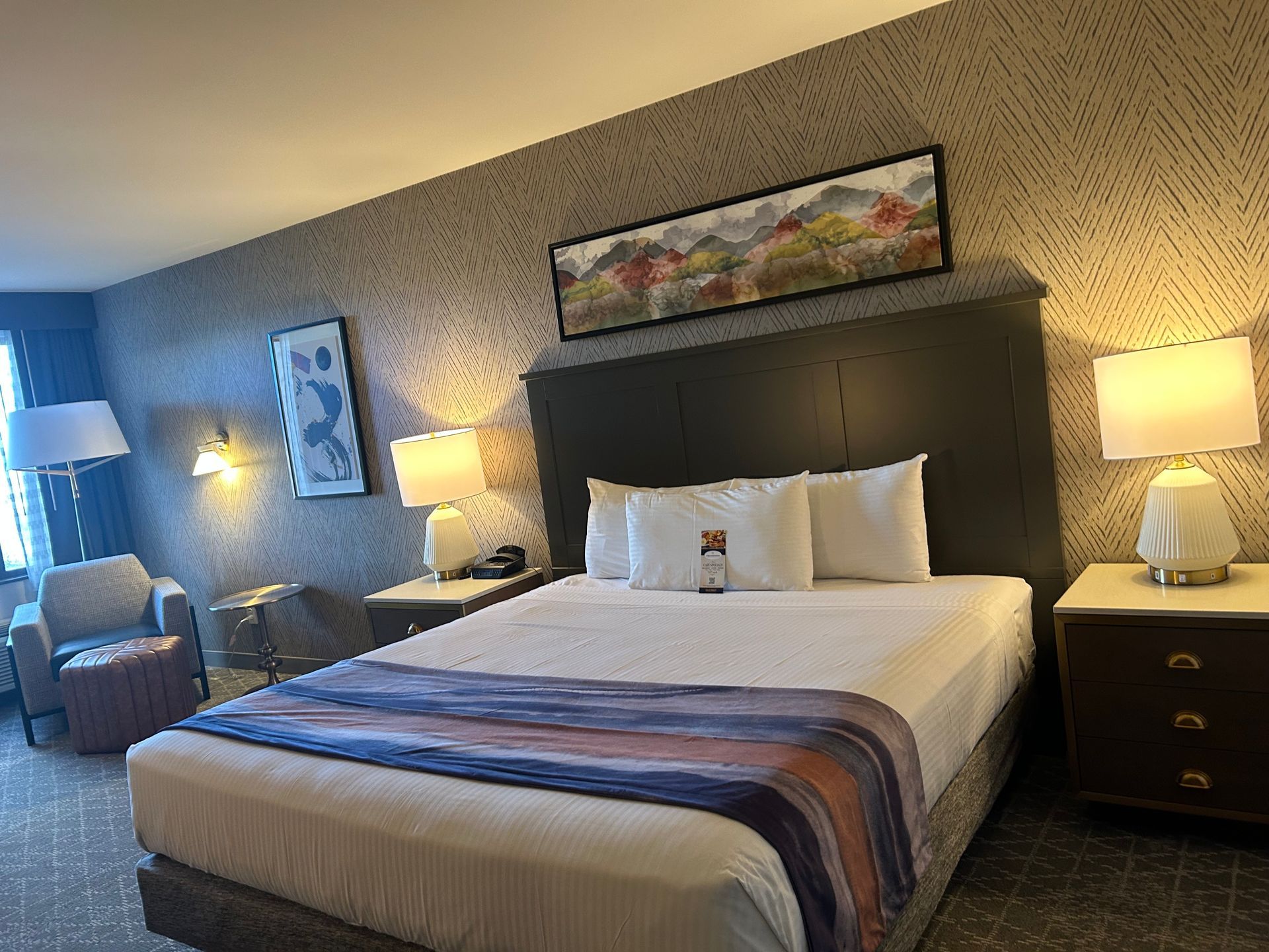 A hotel room with a king size bed and a chair.