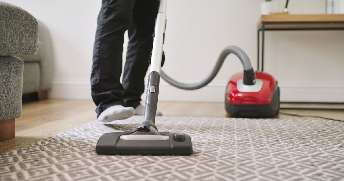 A person is vacuuming a rug in a living room.