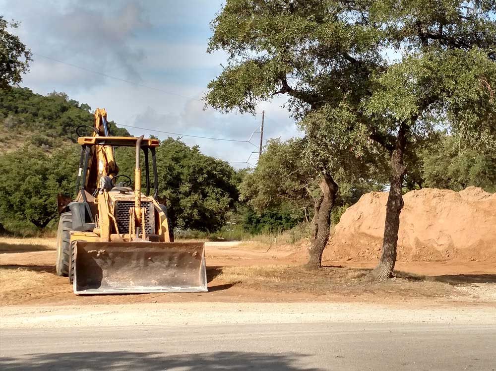 A bulldozer is parked on the side of the road next to a pile of dirt.