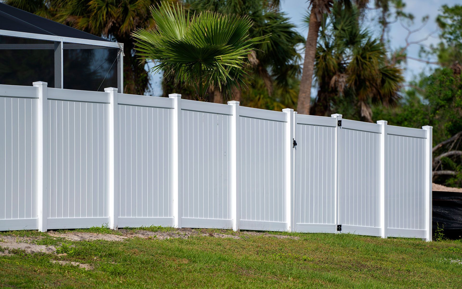 A white fence with a gate is sitting on top of a lush green field.