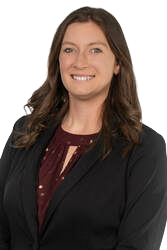Woman in a black blazer and maroon blouse smiling at the camera.