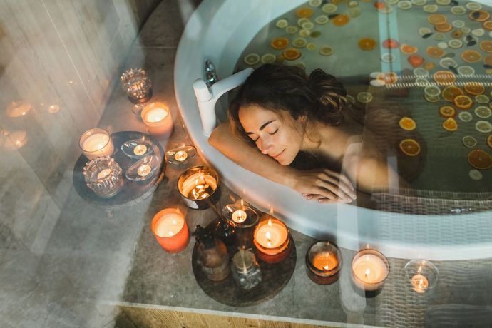 A Woman Is Taking a Bath in A Bathtub Surrounded by Candles - Honolulu, HI - Hawaii Choi Spa