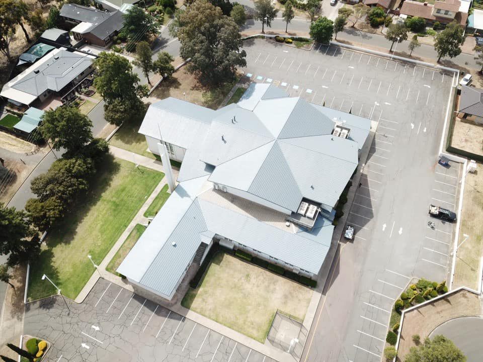 An aerial view of a large building with a parking lot in front of it.