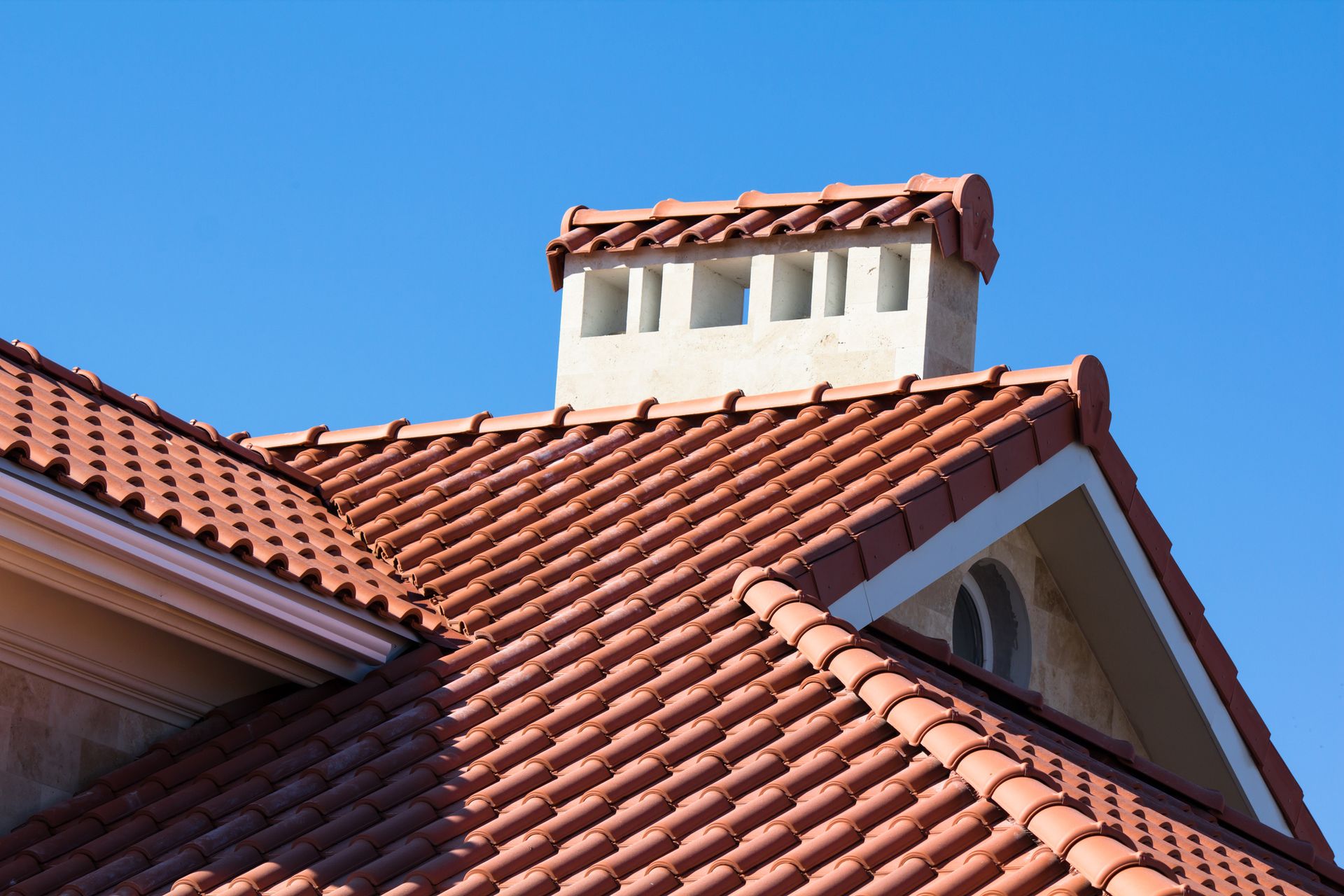 A red tiled roof with a chimney on top of it