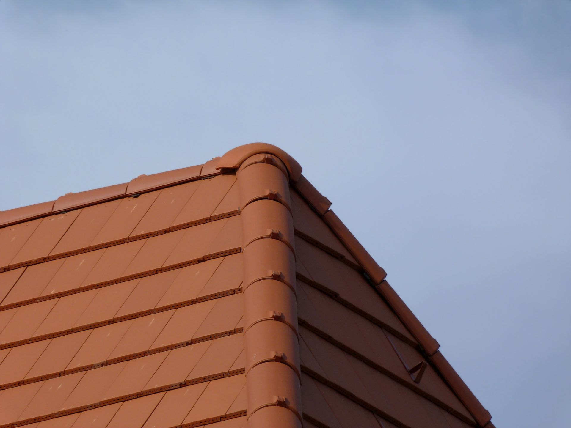 A red tiled roof with a blue sky in the background