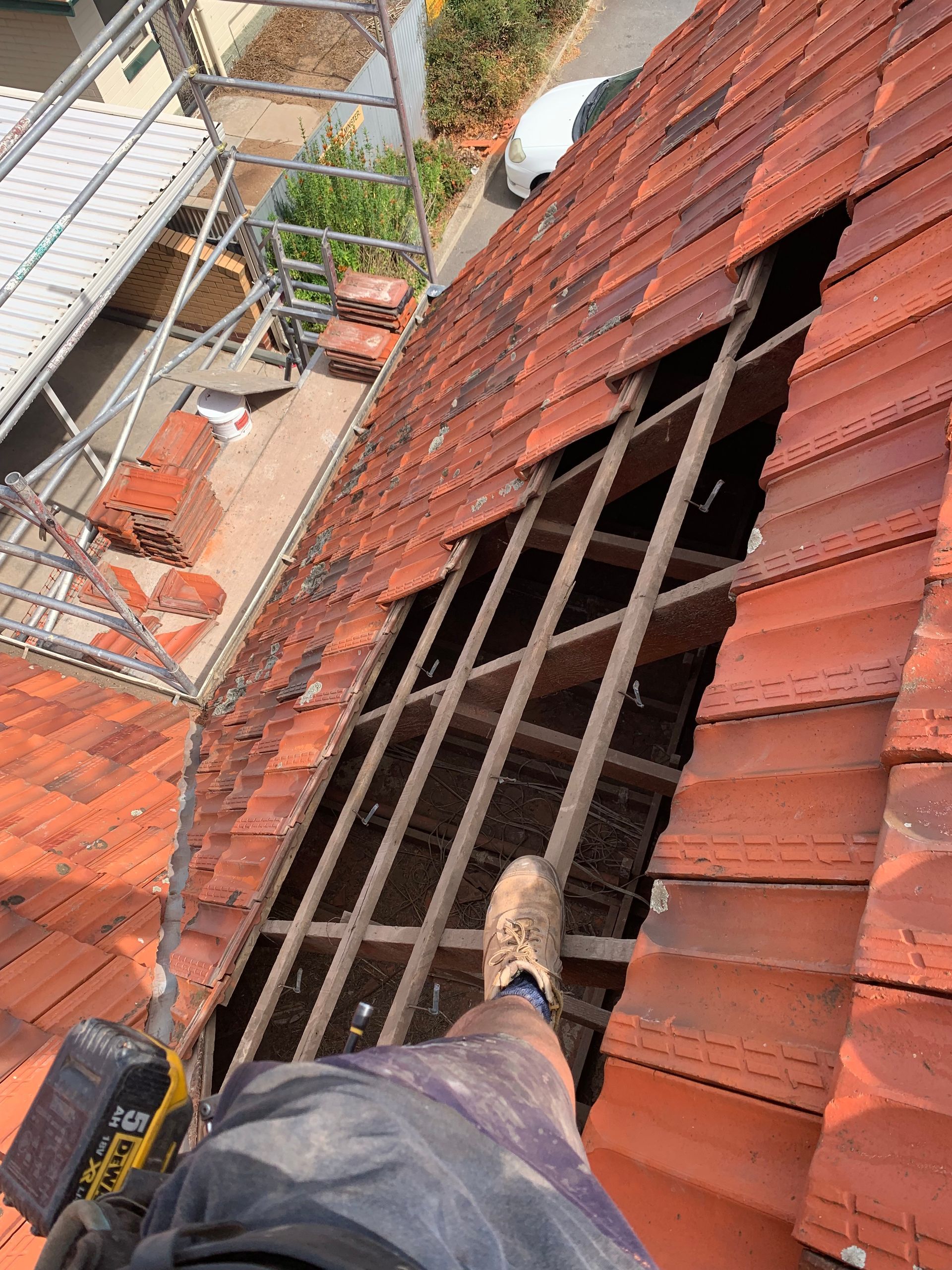 A roof is being repaired with a ladder and scaffolding