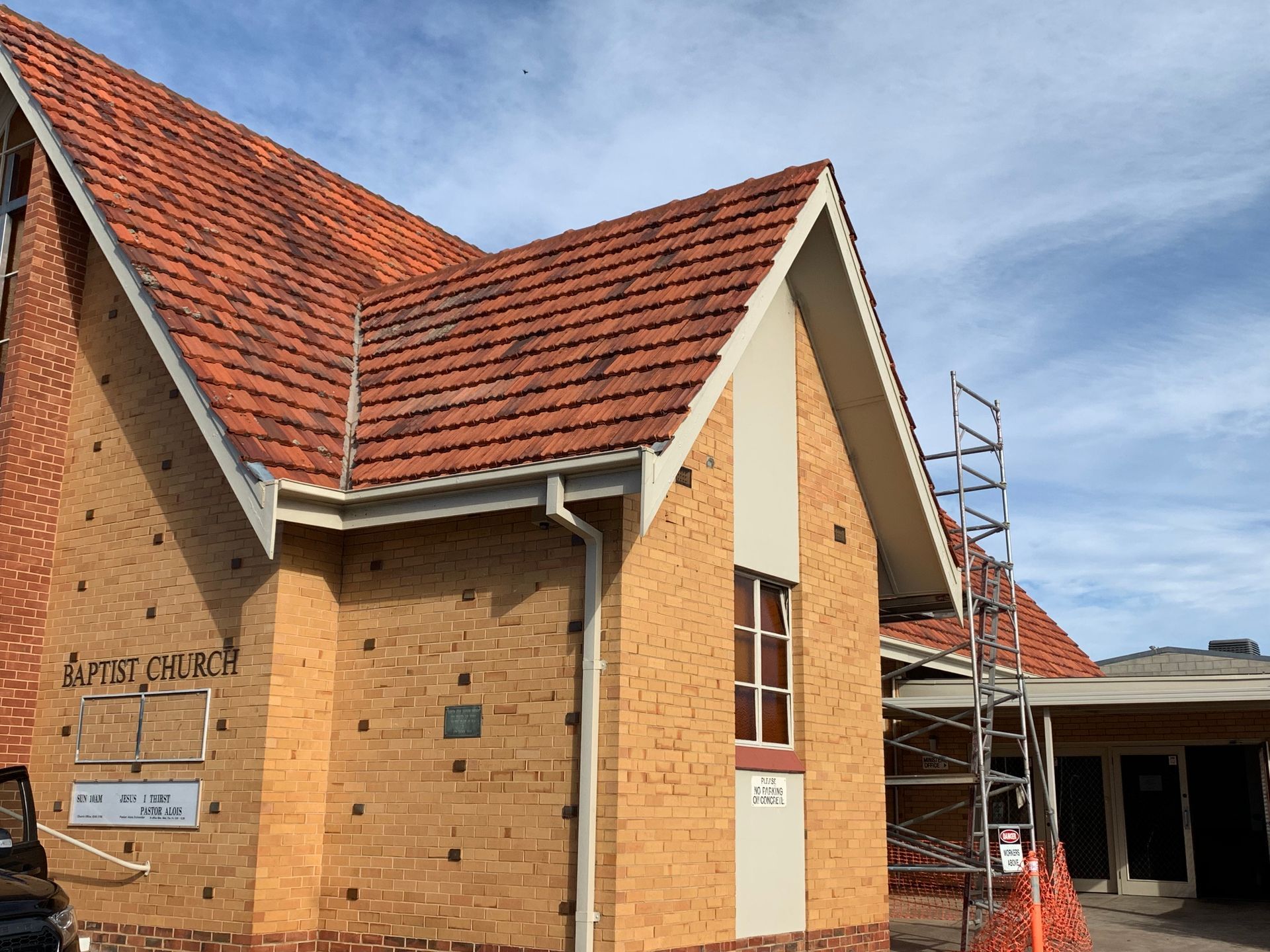 A brick building with a red tiled roof is being remodeled