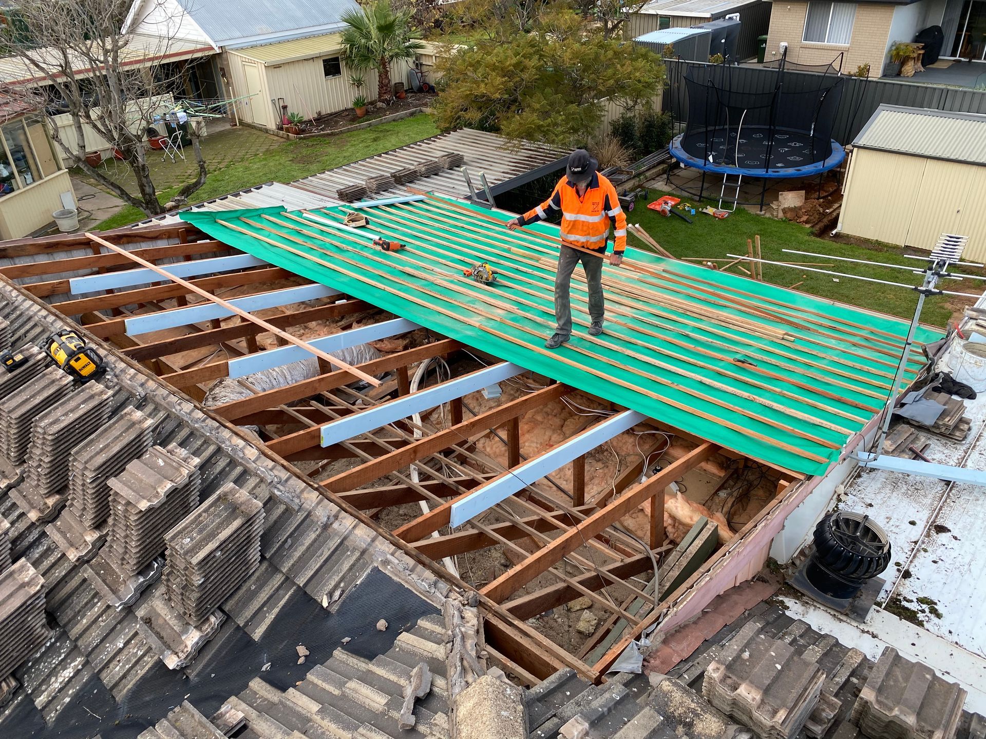 A man is measuring a roof with a tape measure.