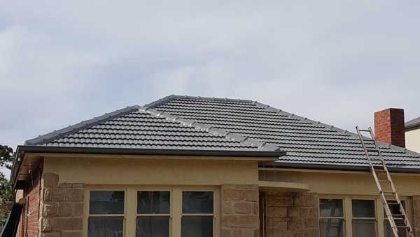 A house with a tiled roof and a ladder on the roof.