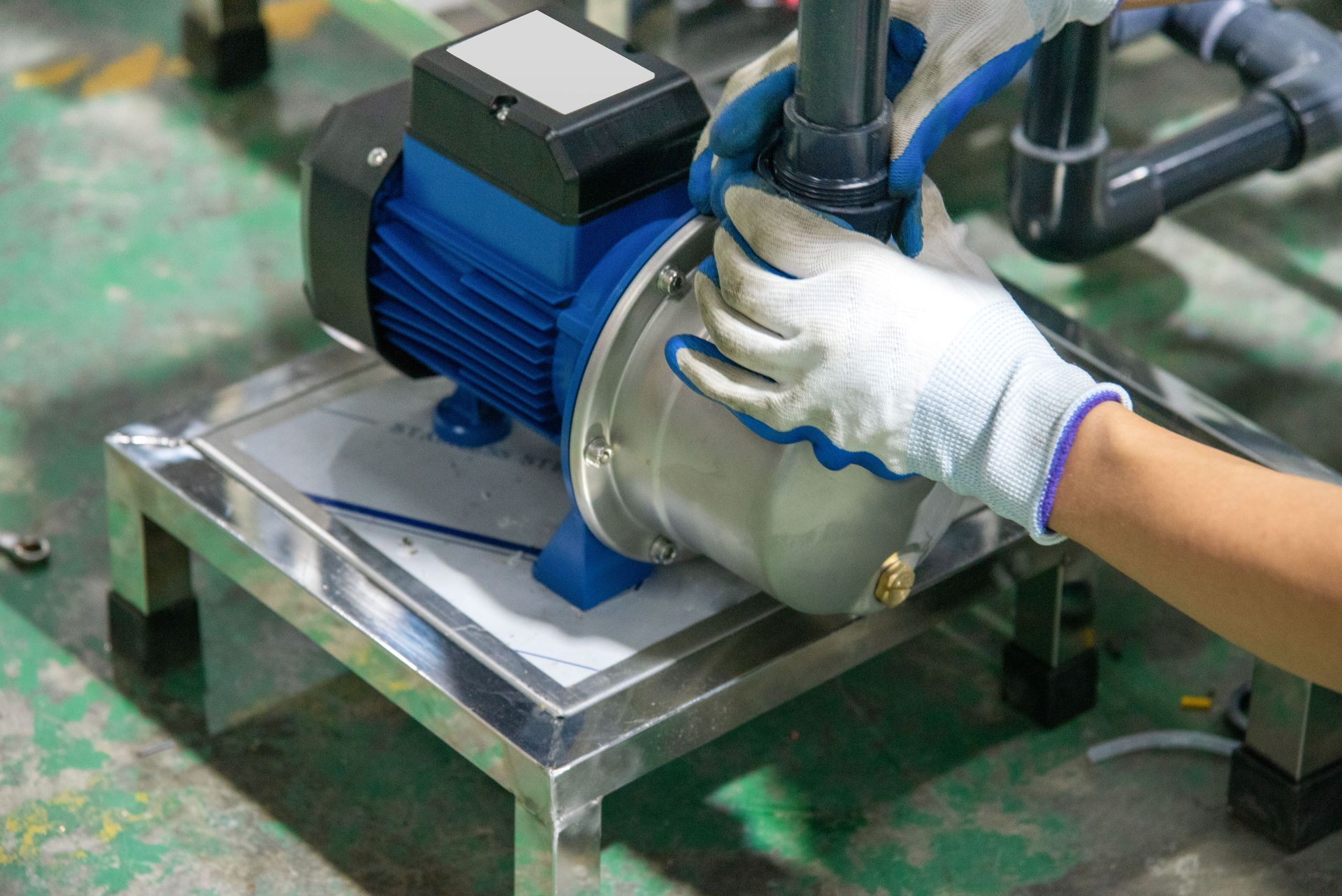 A person maintaining an industrial water pump mounted on a metal frame.