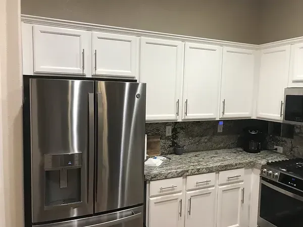 A kitchen with white cabinets and stainless steel appliances.
