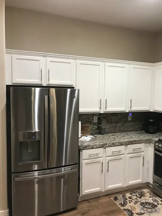 A kitchen with stainless steel appliances and white cabinets.