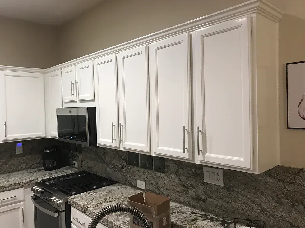 A kitchen with white cabinets and granite counter tops.