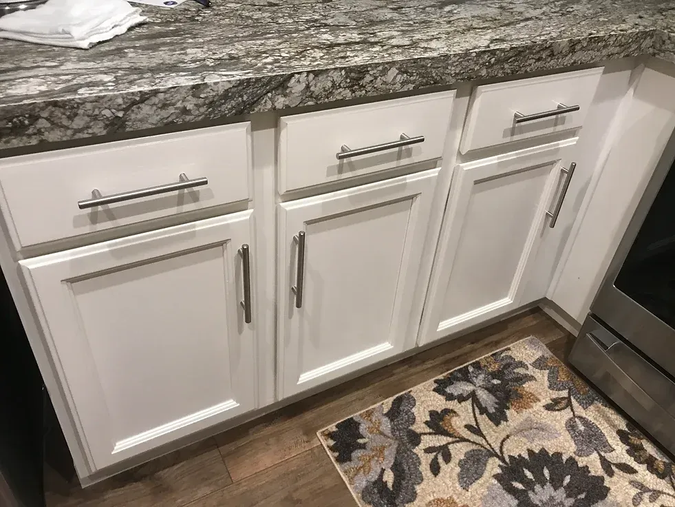 A kitchen with white cabinets and a rug on the floor.