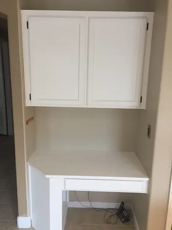 A white desk with a drawer underneath it is in a closet.