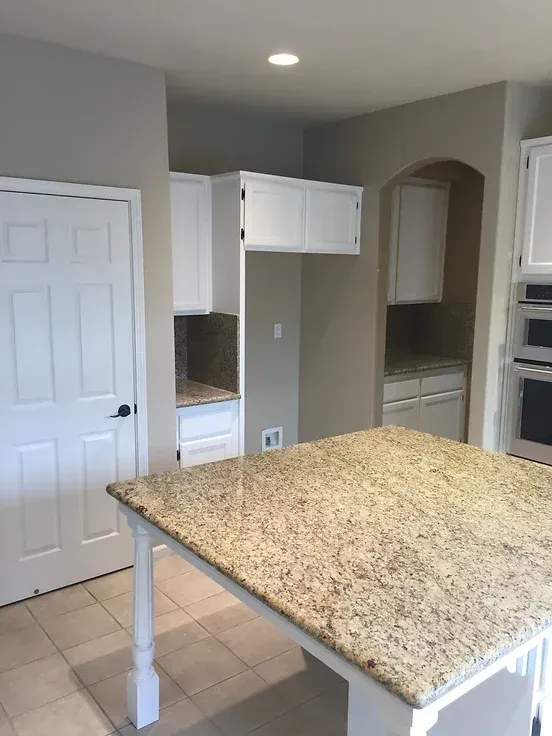 A kitchen with granite counter tops and white cabinets