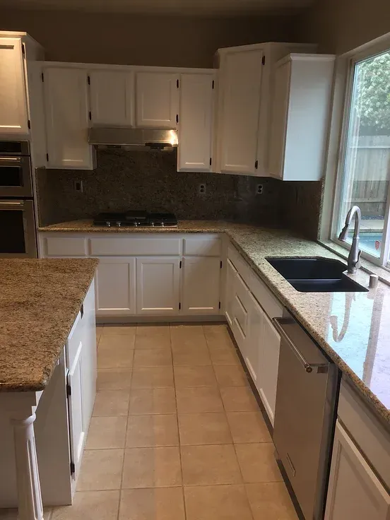 A kitchen with white cabinets and granite counter tops