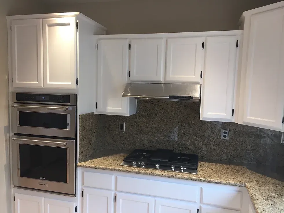 A kitchen with white cabinets and granite counter tops