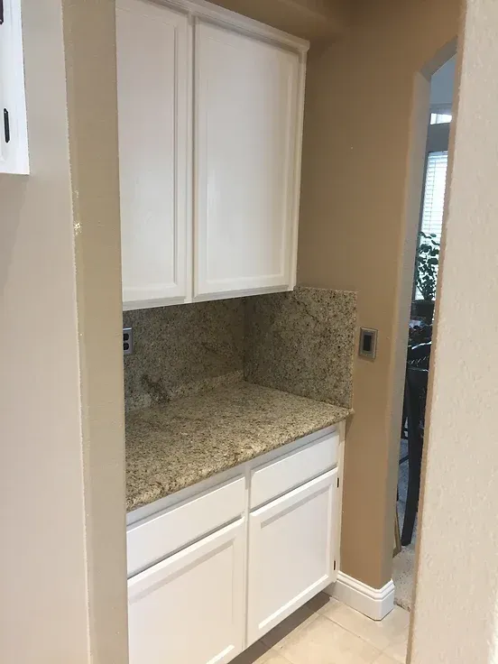 A kitchen with white cabinets and granite counter tops