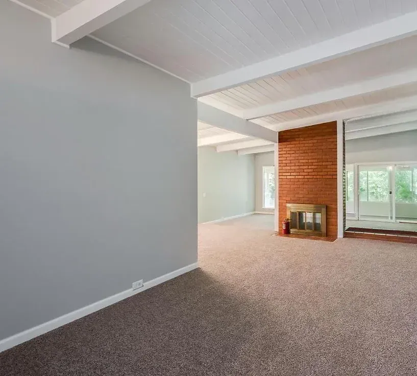 An empty living room with a fireplace and sliding glass doors