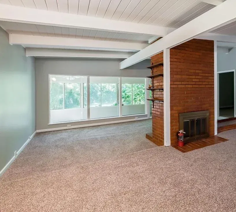 An empty living room with a fireplace and lots of windows