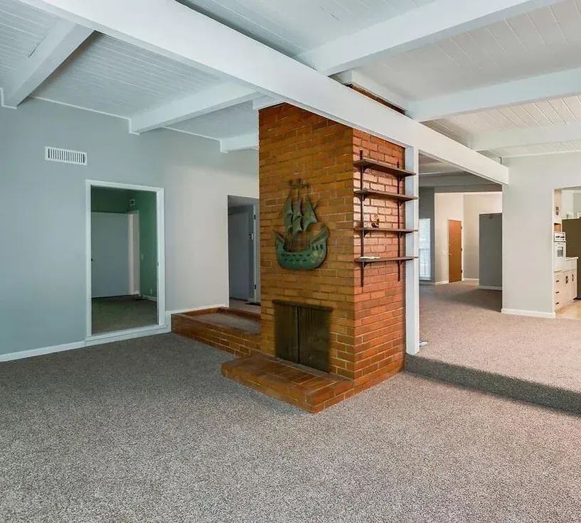 A living room with a brick fireplace and shelves