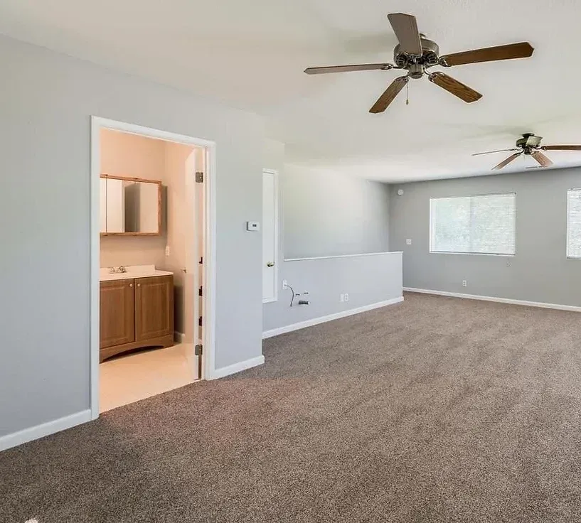 An empty room with a ceiling fan and a bathroom