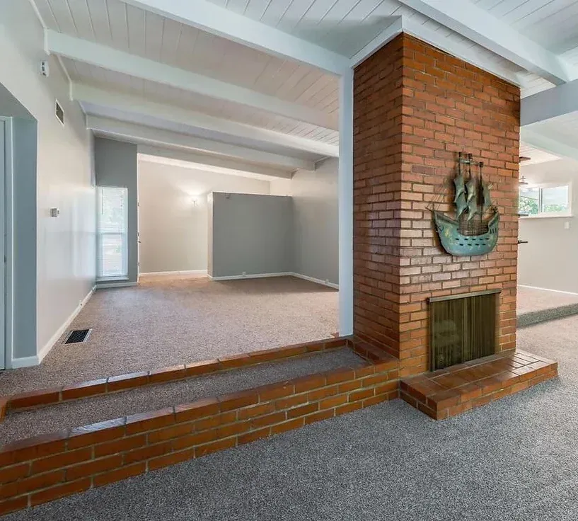 There is a brick fireplace in the middle of the room.
