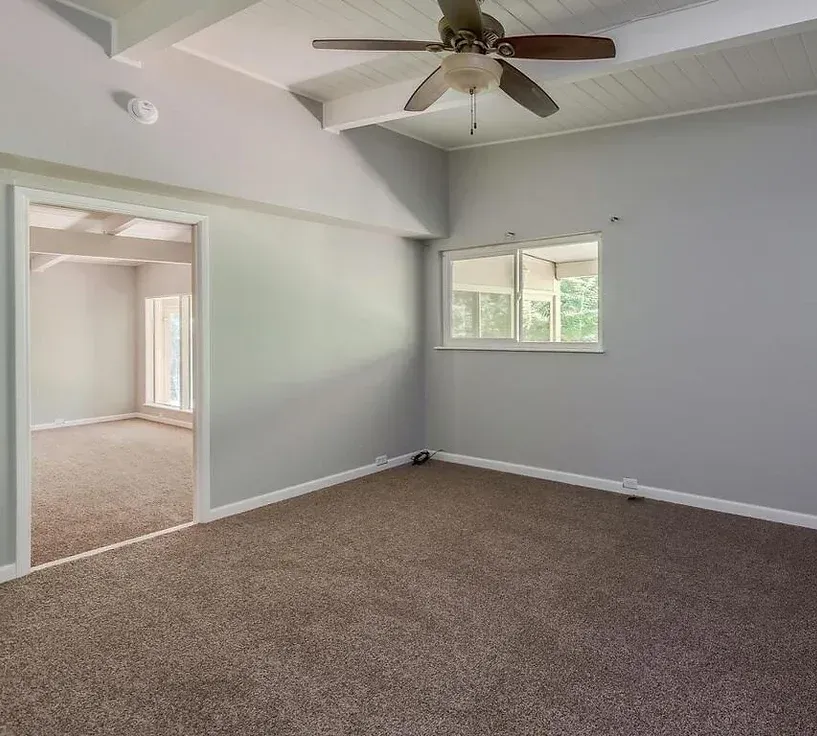 An empty room with a ceiling fan and a window