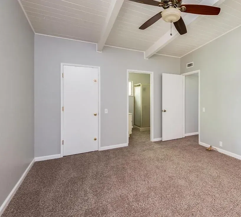 An empty bedroom with a ceiling fan hanging from the ceiling