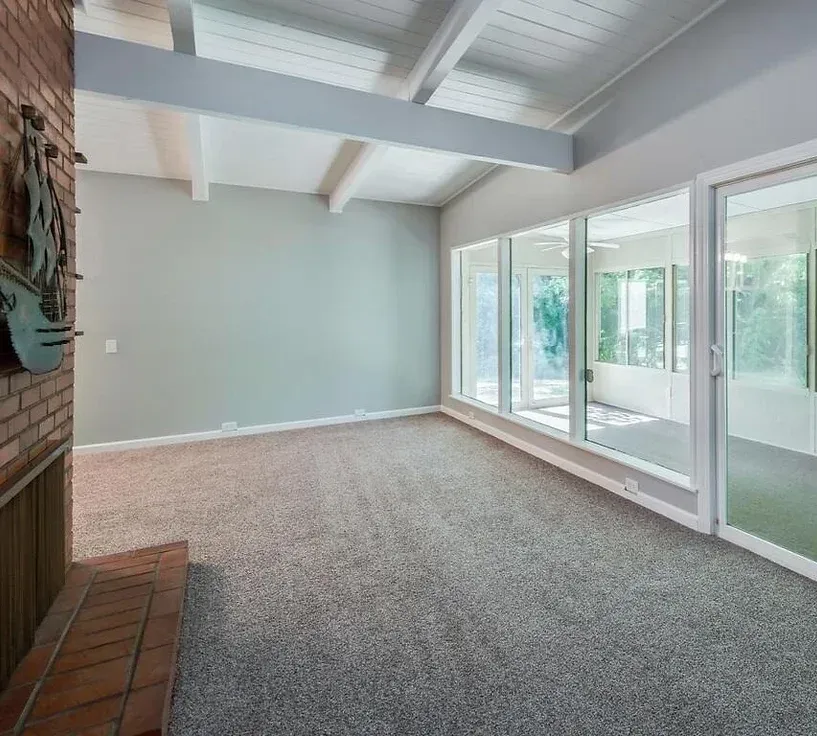 An empty living room with a fireplace and lots of windows.